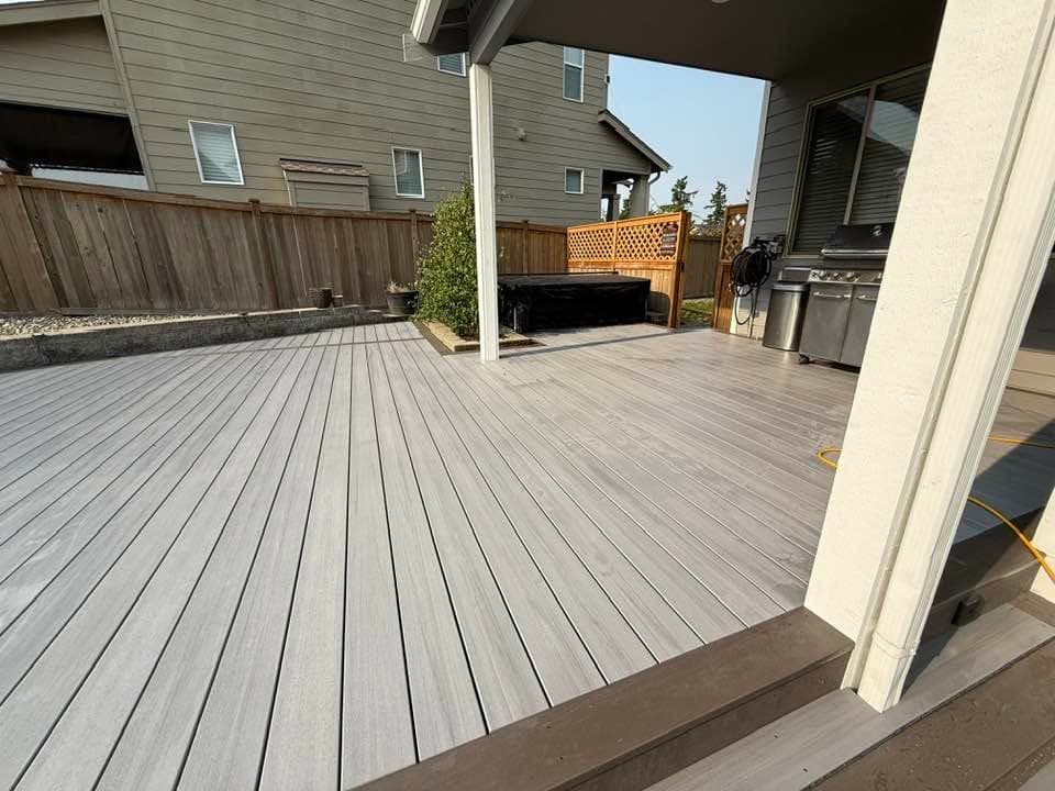 Grey composite decking running under a covered patio beside a built-in grill area