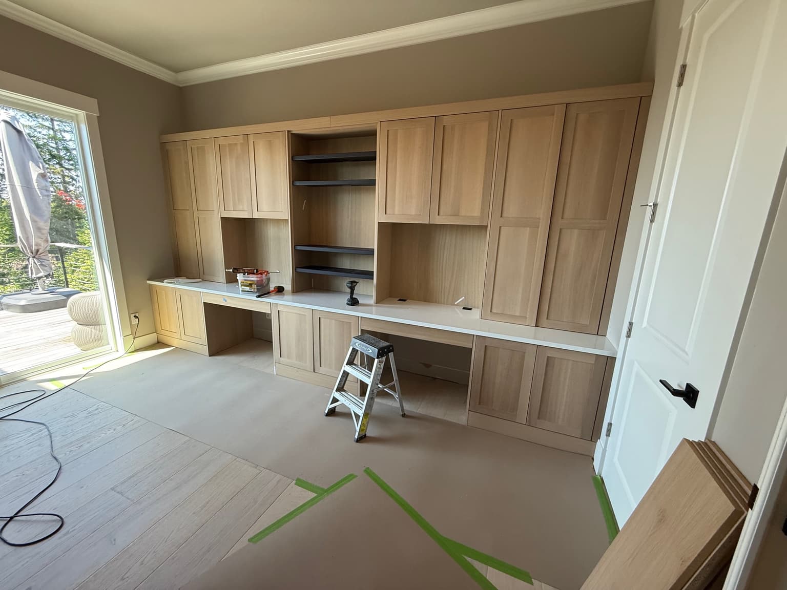 Full-wall built-in home office cabinetry in white oak with a quartz desk top, built by Best Pro Contractors